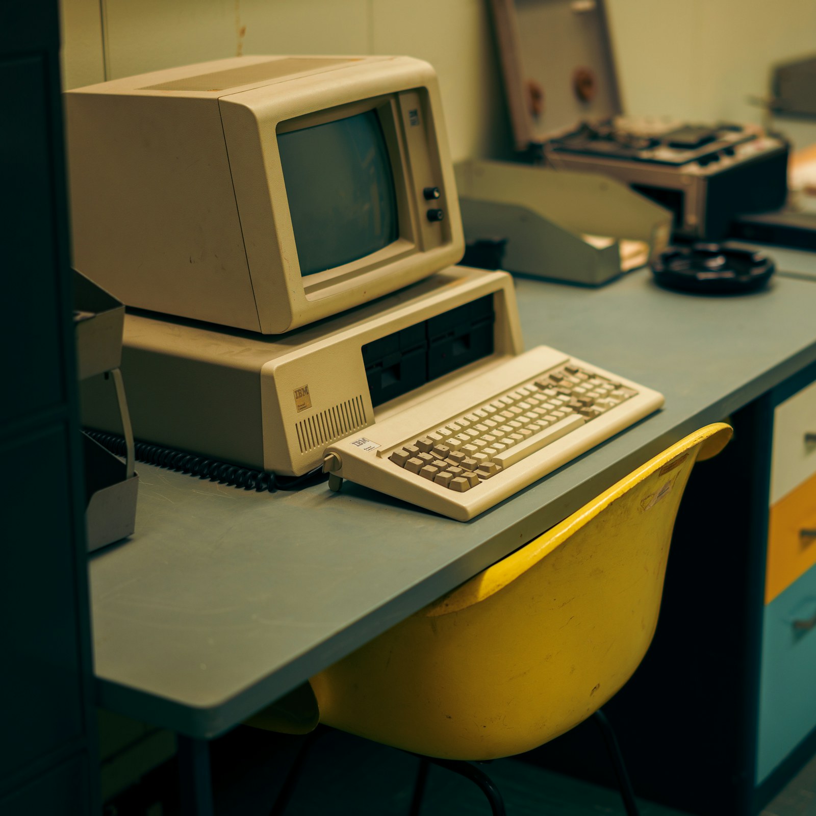 A beige vintage computer with a CRT monitor sitting on a blue desk.